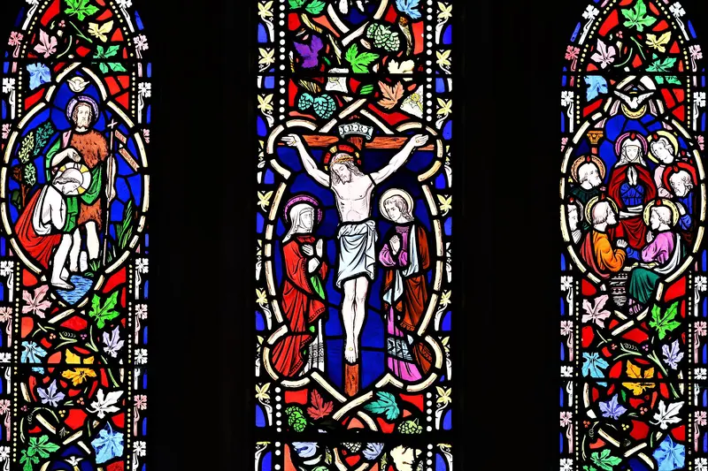 Three lights of richly coloured Victorian stained glass with Gospel scenes in red, blue and green