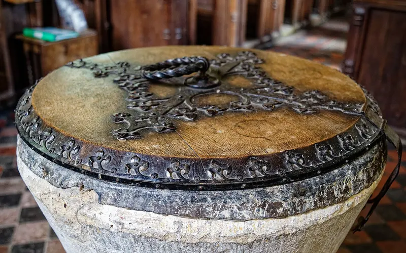 A stone baptismal font with an old wooden cover decorated with ironwork