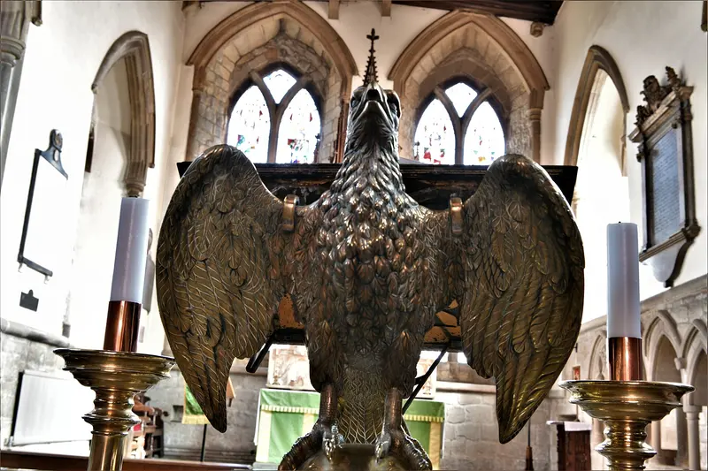 A brass eagle lectern with outspread wings, flanked by candlesticks, in a church chancel